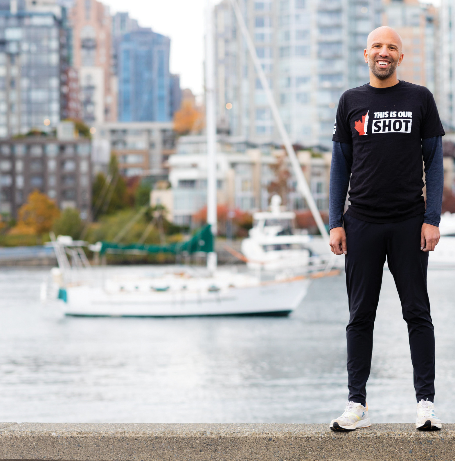 Dr Michael Schwandt stands in front of the Vancouver sea wall in running gear.