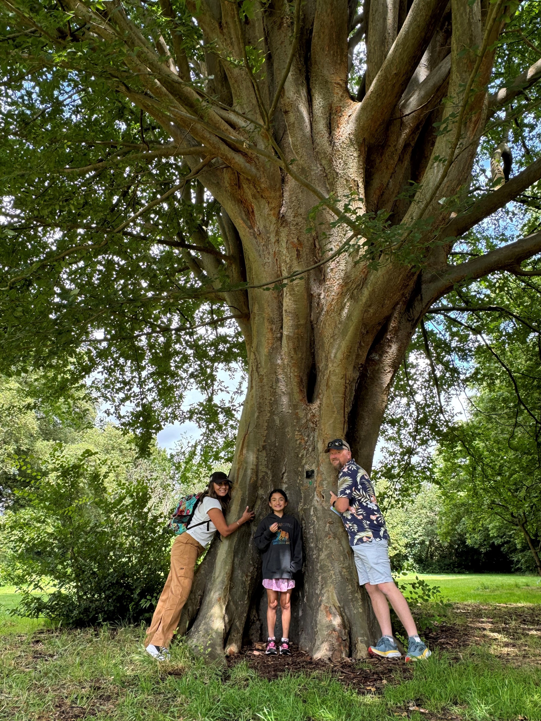 Dr Chahal with her family standing in front of a large tree.