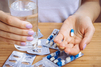 A patient holds an antibiotic and a glass of water