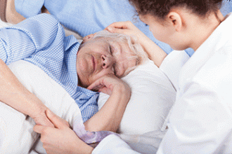 A doctor comforts a patient lying in a hospital bed