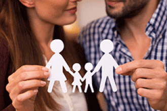 A couple holds paper cutouts of a family with two children