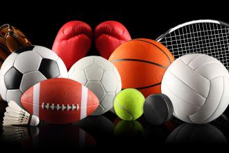 A collection of sports equipment, including a soccer ball, a basketball, a football, a baseball glove, a tennis racquet, and boxing gloves