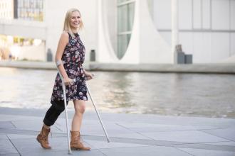 A woman walks with a knee brace and crutches