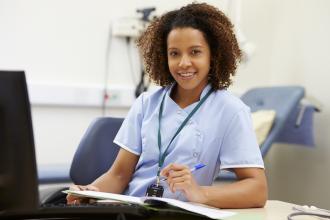 A medical office assistant sits at a computer