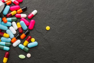 An open pill bottle with a variety of medications spilling out