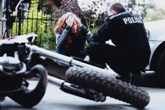 A police officer attends to a woman after a motorcycle accident