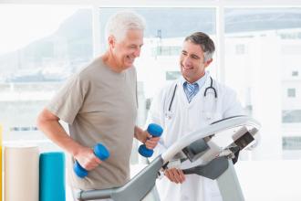 A man exercises while his doctor stands beside him