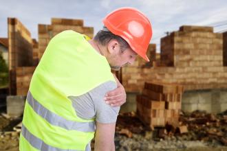 A construction worker holds his shoulder in pain