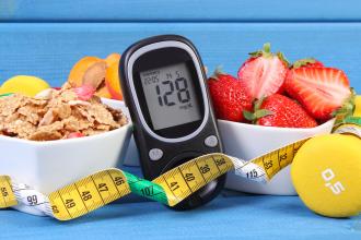 A bowl of cereal, a bowl of strawberries, a blood glucose meter, a tape measure, and free weights