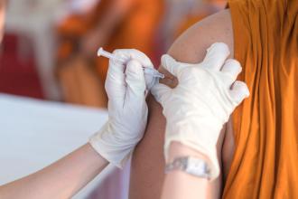 A person receives a needle to their upper arm.