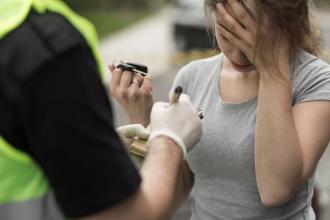 A woman hands her keys to a police officer, looking distraught