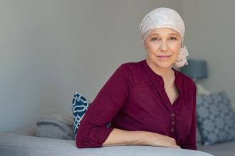 A woman with a scarf on her head sits on a bed
