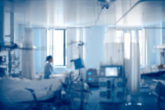 A patient sits on a bed in a hospital room