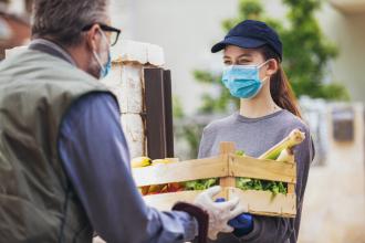A volunteer delivers a box of food to a senior