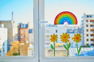 A cheerful window with flowers and a rainbow painted on it