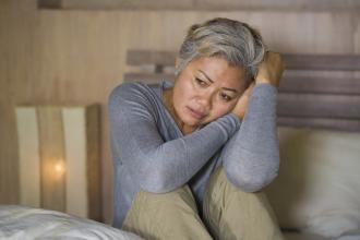 Depressed middle-aged female, sitting on bed