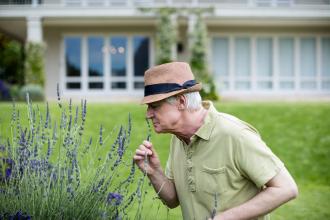 A senior smells flowers in a garden