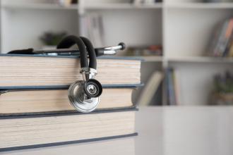 A stethoscope sits on top of a stack of books