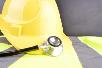 A hardhat and a stethoscope sit on top of a high-visibility vest