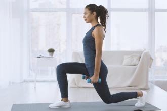 A woman does a lunge while holding hand weights