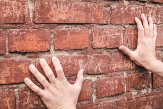 Hands pressed against a brick wall