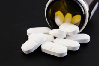 A bottle of penicillin tablets spills out onto a table