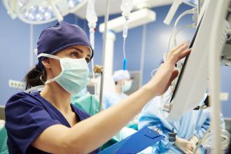 A doctor watches a patient's heart rate monitor during a surgery