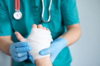 A doctor treats a workplace injury to a hand
