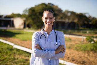 A doctor stands outside in a rural area