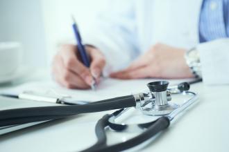 A doctor sits at a board room table writing notes