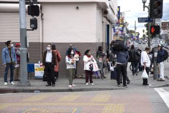 People walking along the sidewalk wearing masks