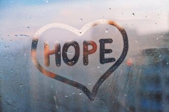 A heart with the word "Hope" in it has been drawn into condensation on a window