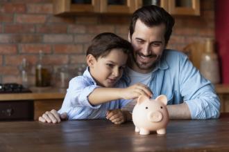 A father and son put money into a piggy bank