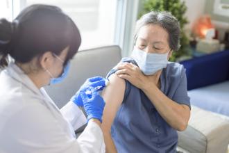 A doctor administers a vaccination to an Asian senior