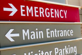 A sign outside a hospital with an arrow pointing to the emergency department
