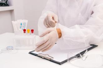 A lab technician dons gloves in preparation for testing samples