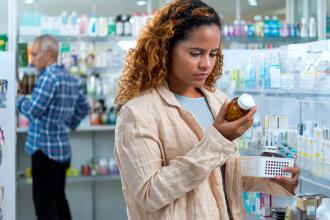 A woman reads a label on a bottle of vitamins