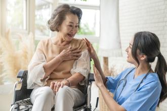 A doctor cares for an Asian Canadian senior in a wheelchair