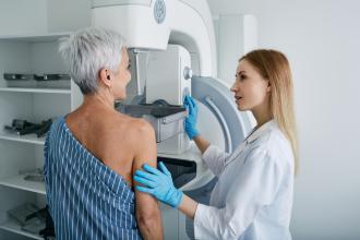 A radiologist performs a mammogram on a middle-aged woman