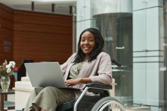 A woman uses a laptop while sitting in a wheelchair.