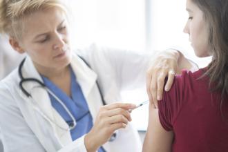 A teenage girl receives a vaccination.