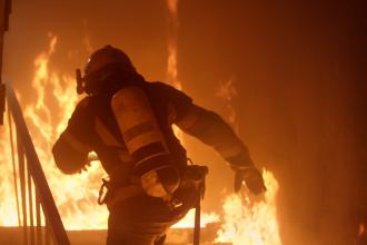 rave Firefighter Runs Up The Stairs. Raging Fire is Seen Everywhere.