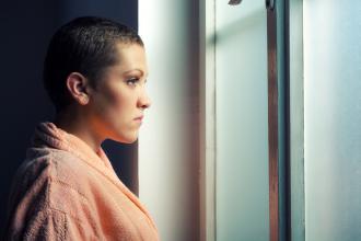 Young cancer patient looking out window