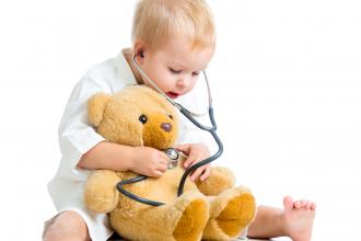 Child using a stethoscope and his senses to look after his teddy bear patient