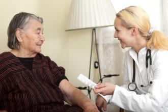 Elderly patient being given a package of pills by a doctor