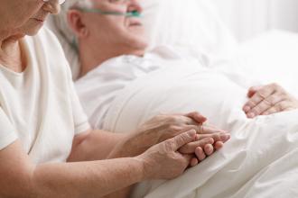 End of life care at a hospice. Married couple with the male hooked up to oxygen