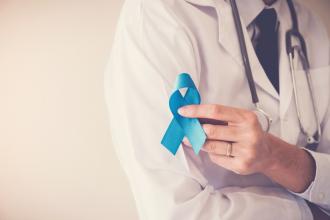 A doctor holds a blue ribbon for prostate cancer awareness