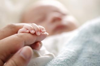 Newborn baby grasping parent's finger