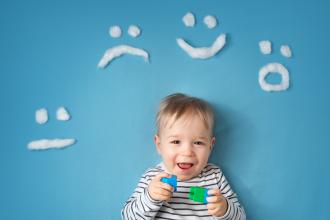 Little smiling boy on a blue background with different emotions in wool