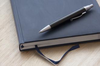 A pen sits on top of a journal